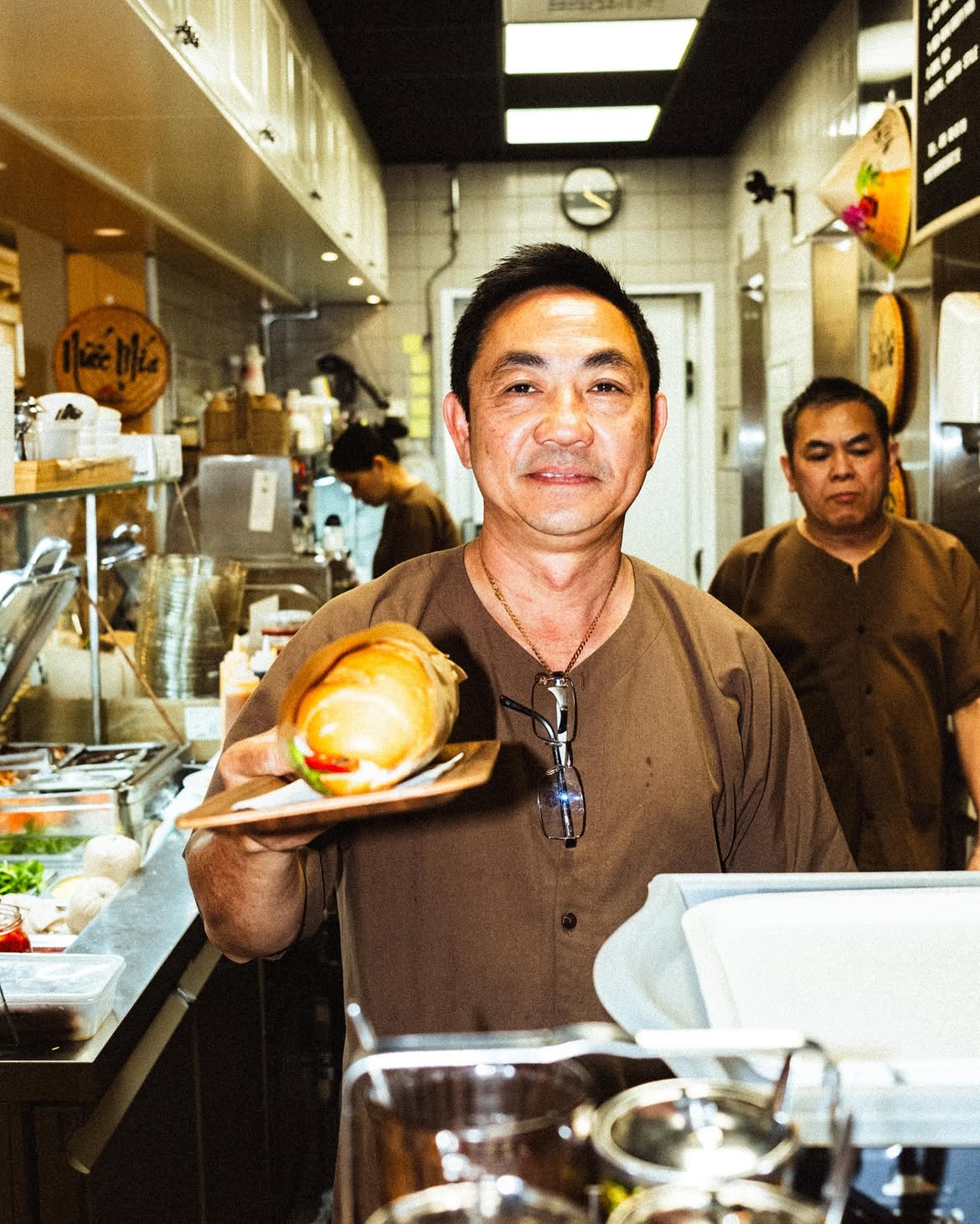 Banh Mi shopkeeper serving a freshly made sandwich